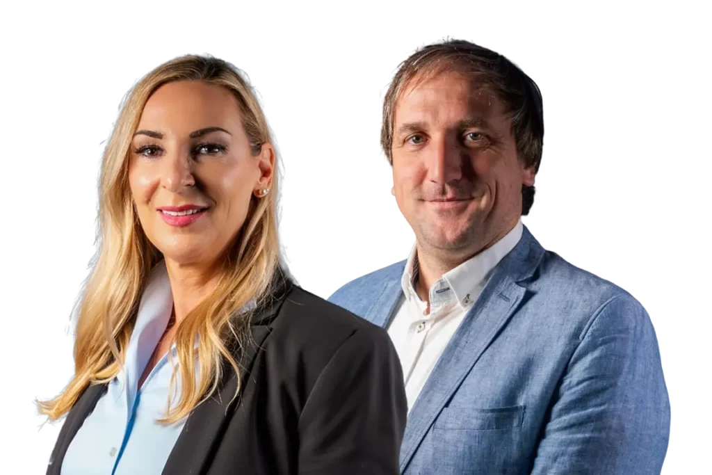 A woman in a black blazer and a man in a blue blazer stand side by side.